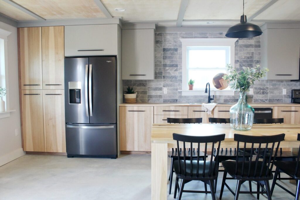 Modern wood and grey kitchen with backsplash tile and black stainless refrigetator